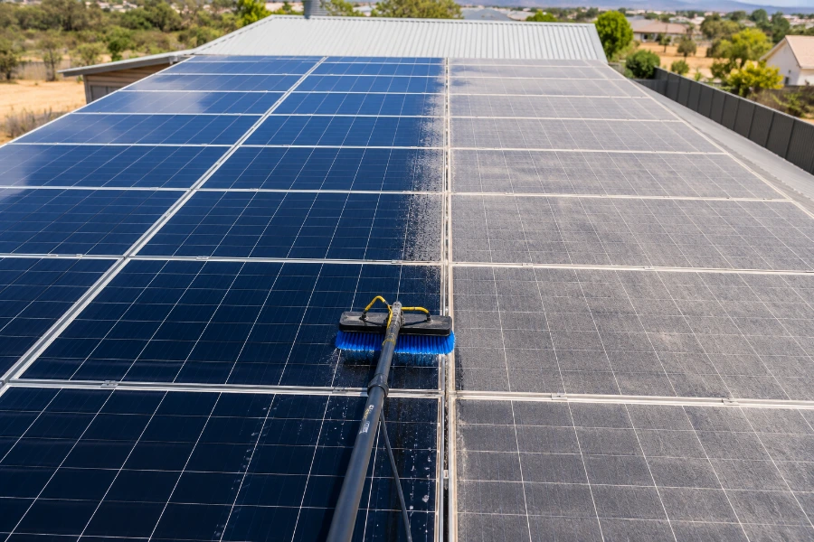 Solar panel array mid-clean showing the front-to-back cleaning order, with finished panels clean and remaining rows still soiled
