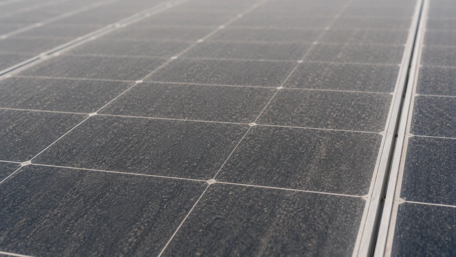Close-up of a dirty solar panel covered in dust and salt film with a hazy, non-reflective surface